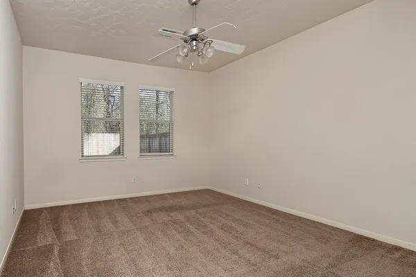 an empty room with a chandelier fan and windows