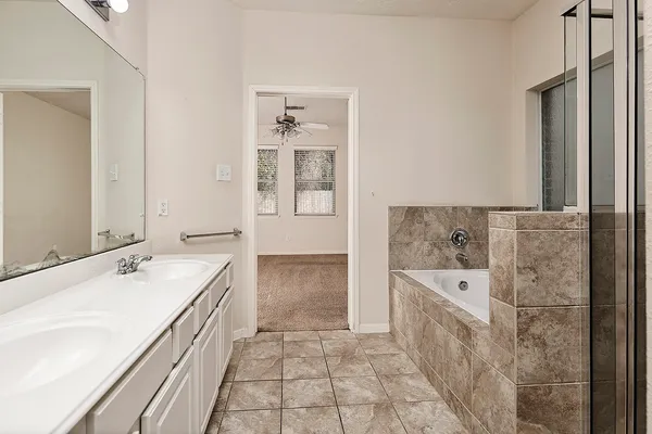 a spacious bathroom with a tub sink and mirror