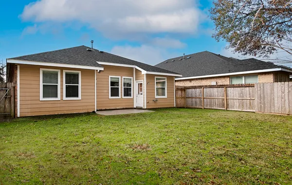 a view of a yard in front of a house with wooden fence