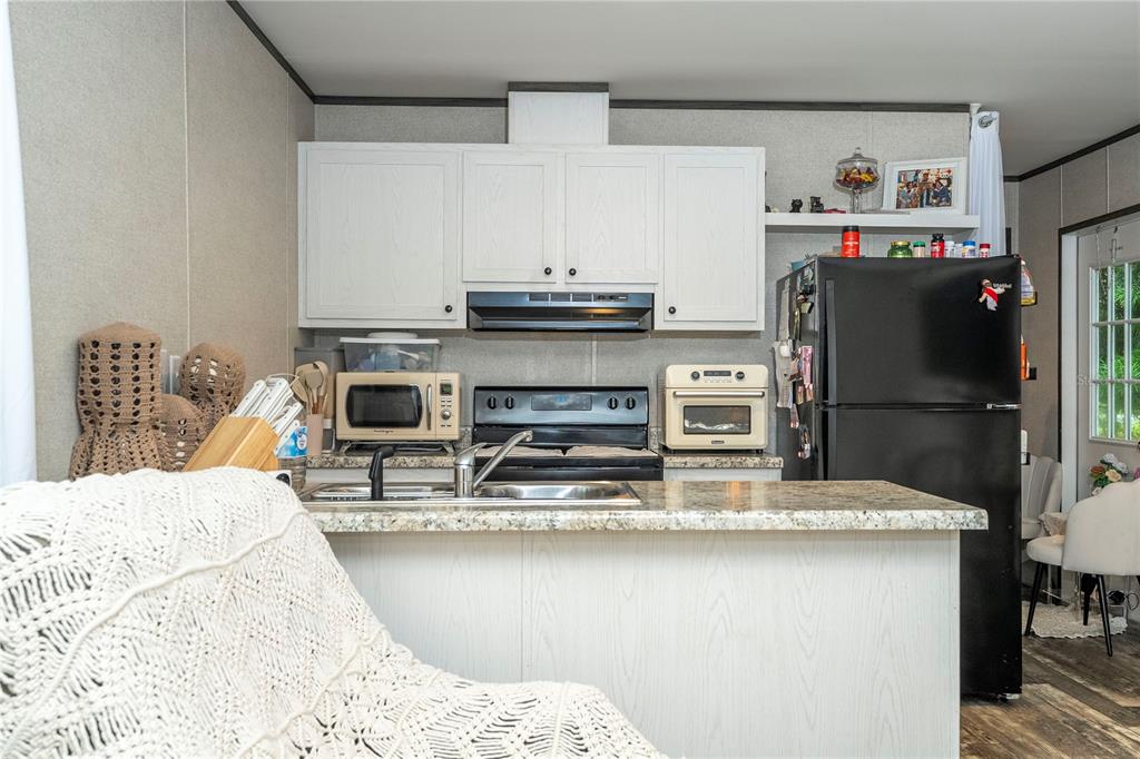 36720 Emeralda Island Road Leesburg, FL 34788 - Photo 16 of 43 a kitchen with stainless steel appliances kitchen island granite countertop a refrigerator a stove and a dining table with wooden floor