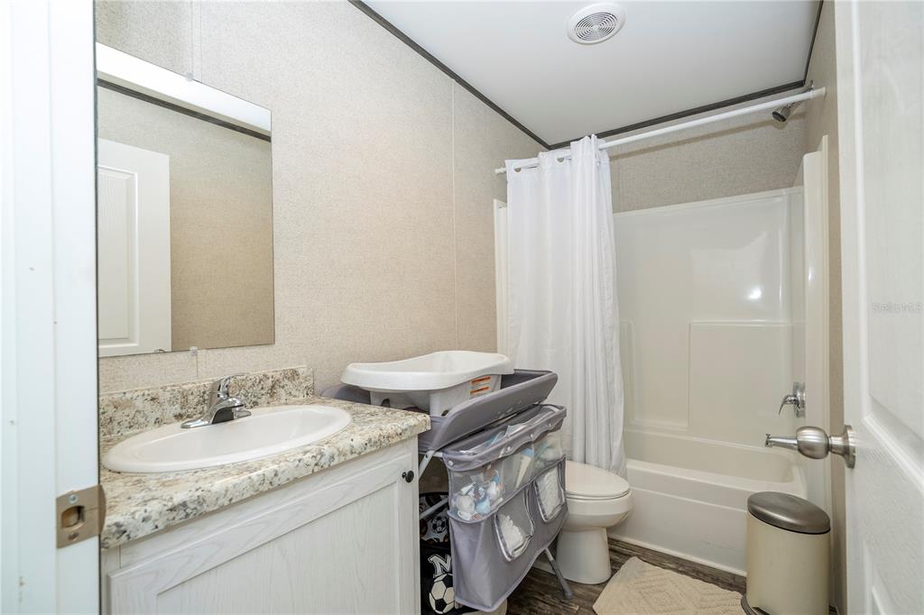 36720 Emeralda Island Road Leesburg, FL 34788 - Photo 19 of 43 a bathroom with a granite countertop sink a toilet a mirror and shower