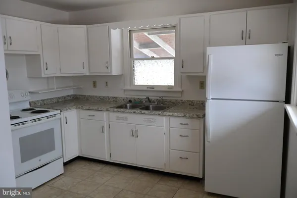 a kitchen with granite countertop white cabinets appliances a sink and a window
