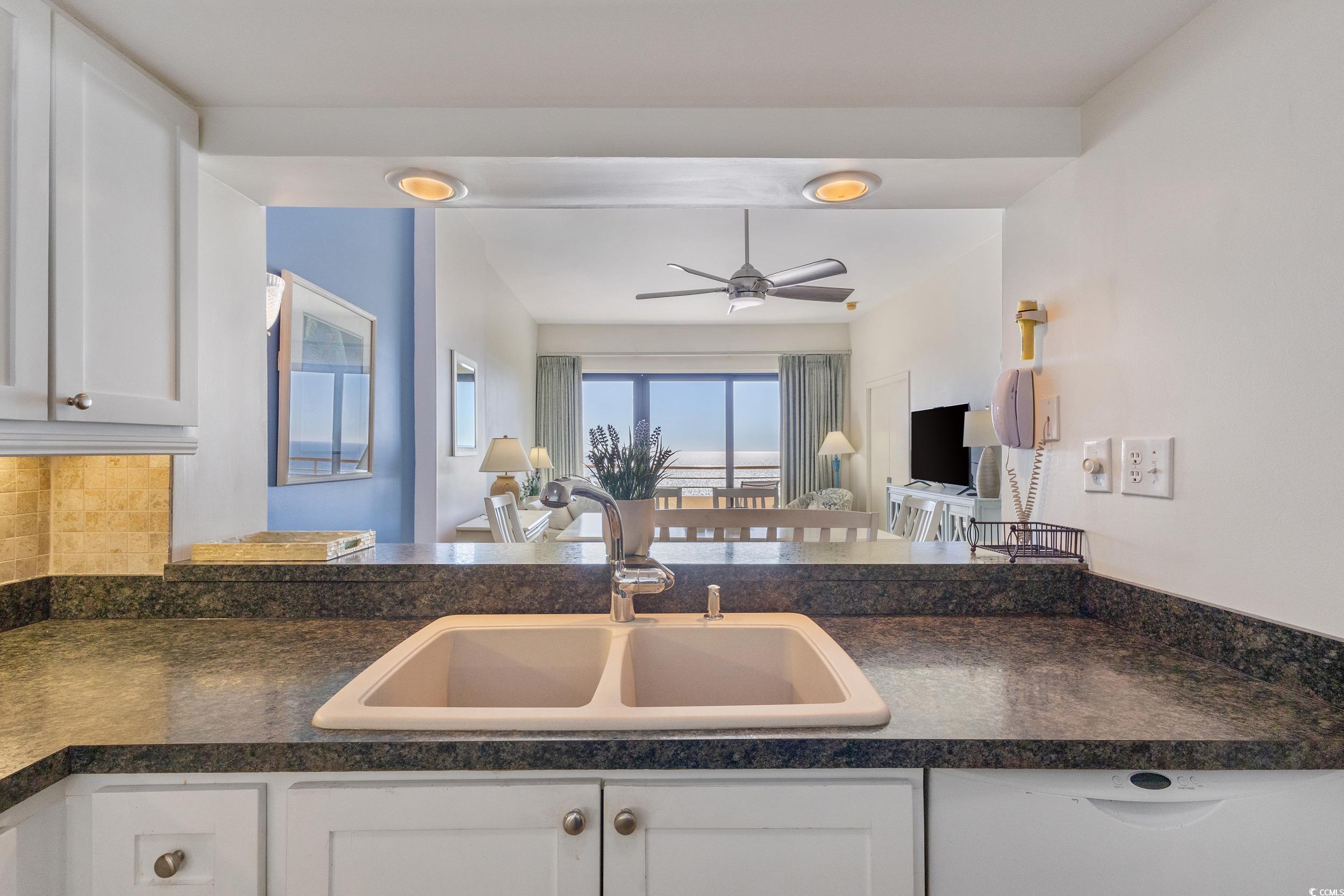 100 Ocean Creek Drive, Unit G14 Myrtle Beach, SC 29572 - Photo 40 of 40 Kitchen with dark countertops, white cabinets, open floor plan, and a ceiling fan