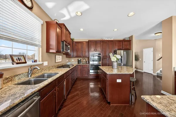 a kitchen with kitchen island granite countertop a sink stainless steel appliances and cabinets
