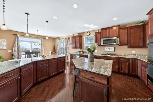 a kitchen with stainless steel appliances granite countertop wooden cabinets a stove a sink and a wooden floors