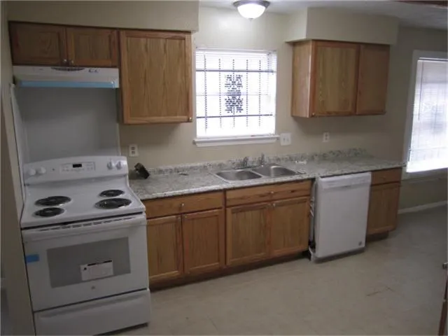 a kitchen with granite countertop a sink stove and cabinets