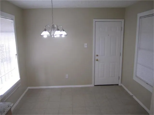 an empty room that has a chandelier fan and windows