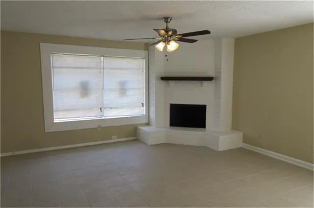 a view of an empty room with a fireplace and a window