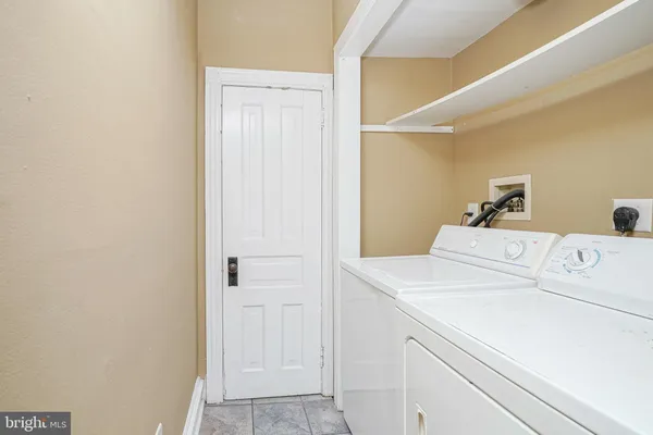 a view of an empty room with wooden floor and a bathroom