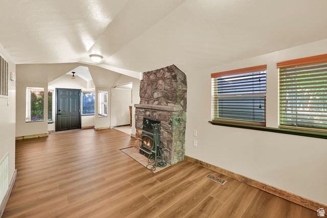655 Ogden Canyon Road Ogden, UT 84401 - Photo 49 of 50 Spacious living area featuring wood-finish flooring, a prominent stone fireplace with a wood-burning stove, and multiple windows