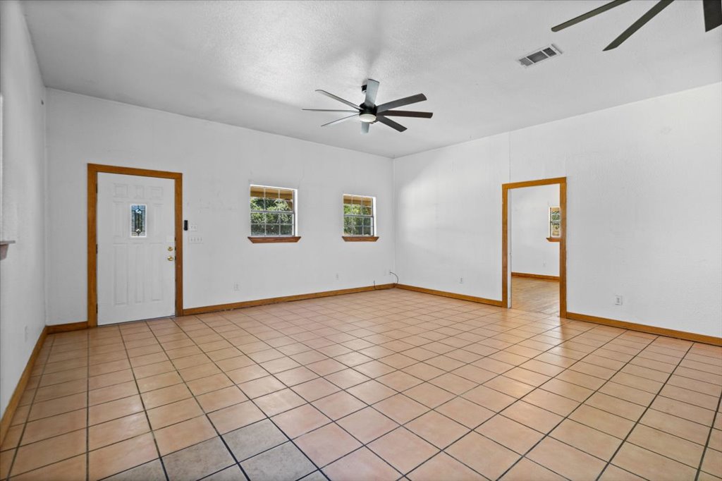 555 Harmon Hills Road, Unit A Dripping Springs, TX 78620 - Photo 11 of 29 A spacious living area features tiled flooring and dual ceiling fans, offering a relaxed and breezy ambiance.