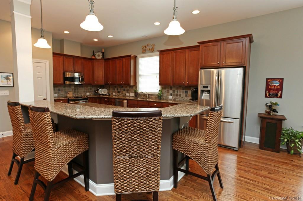 671 Revival Row Fort Mill, SC 29708 - Photo 5 of 24 a kitchen with stainless steel appliances granite countertop a stove a sink dishwasher a dining table and chairs with wooden floor
