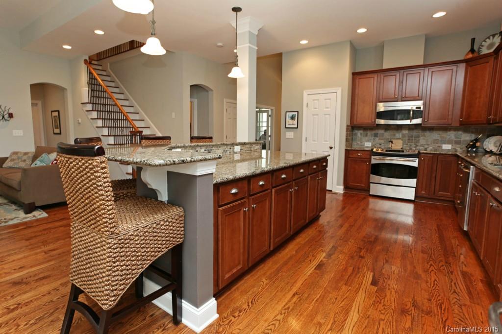 671 Revival Row Fort Mill, SC 29708 - Photo 7 of 24 a large kitchen with stainless steel appliances kitchen island granite countertop a large stove a sink dishwasher and a dining table with wooden floor