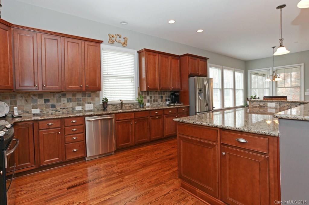 671 Revival Row Fort Mill, SC 29708 - Photo 9 of 24 a kitchen with stainless steel appliances granite countertop wooden cabinets a stove a sink and dishwasher with wooden floor