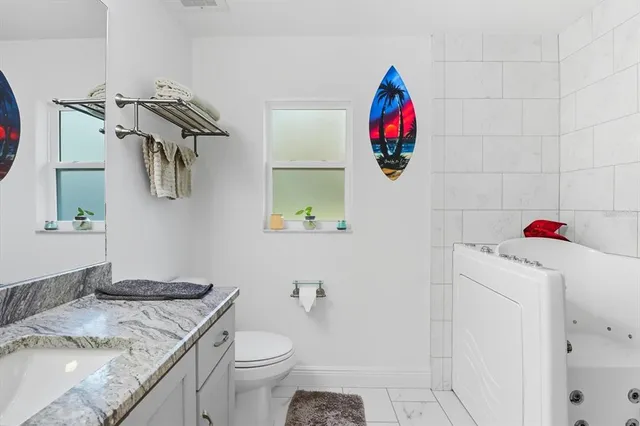 a bathroom with a granite countertop toilet a sink and a mirror