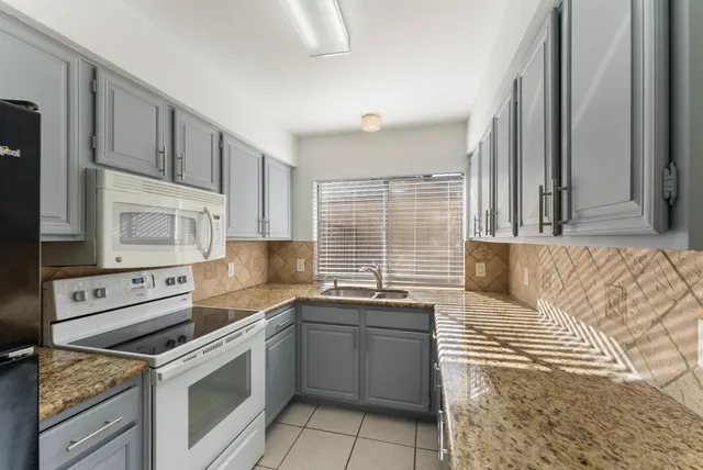 a kitchen with stainless steel appliances granite countertop a sink stove oven and white cabinets