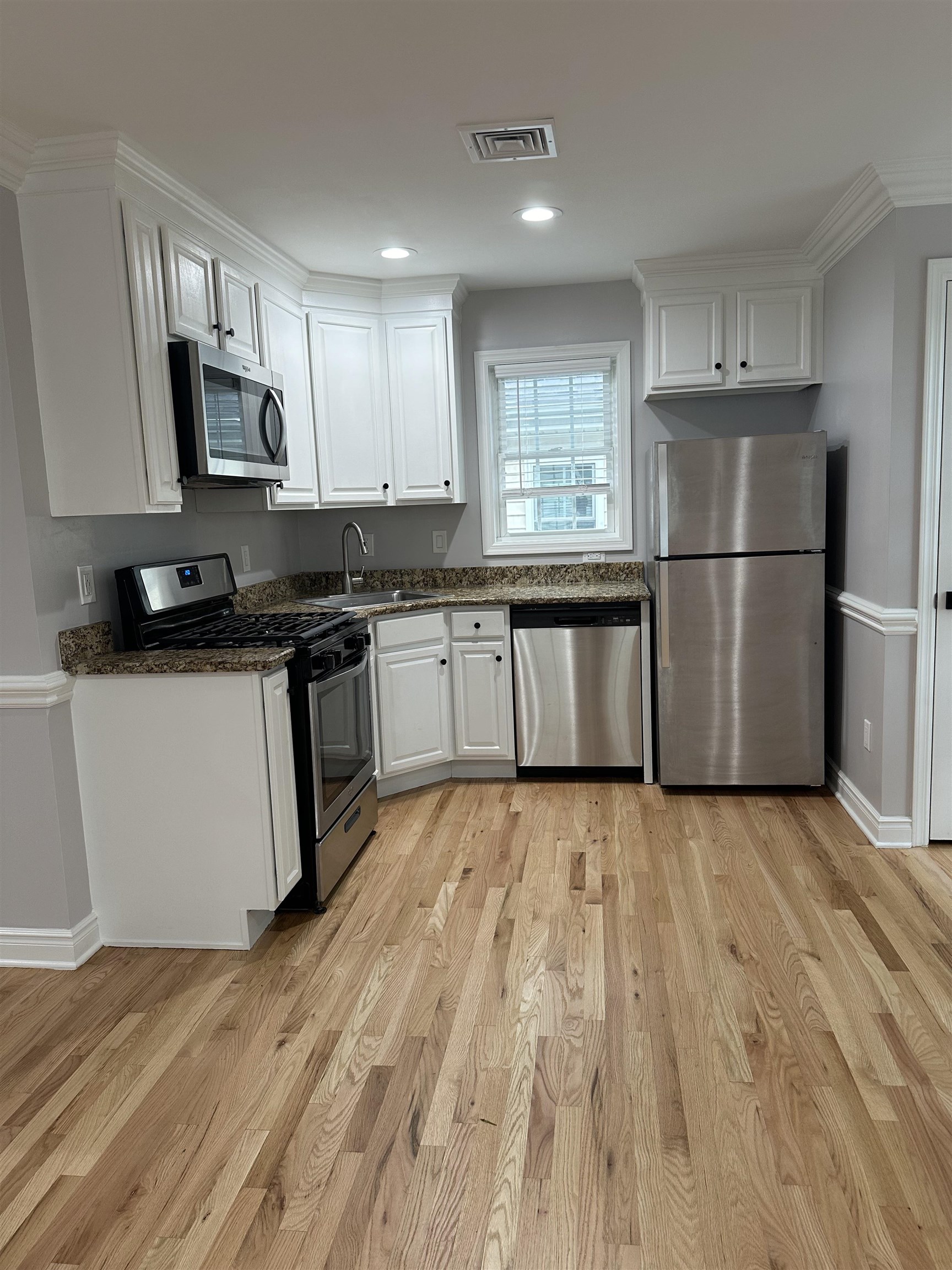 24 New Street, Unit 2 Bayonne, NJ 07002 - Photo 8 of 21 a kitchen with stainless steel appliances granite countertop a stove top oven a sink dishwasher a refrigerator and a microwave with wooden floor