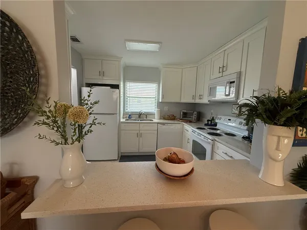 a kitchen with white cabinets and white appliances