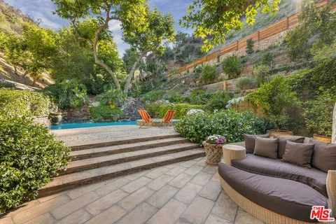 a view of a patio with table and chairs potted plants and large tree