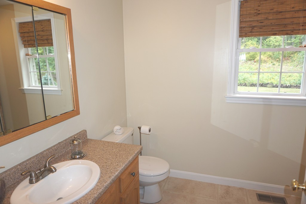 84 Fairview Park Road Sturbridge, MA 01566 - Photo 25 of 30 a bathroom with a granite countertop toilet a sink and a mirror
