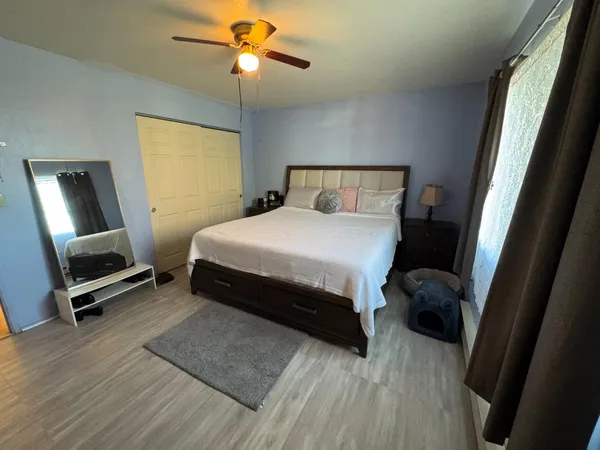 a bedroom with a bed a mirror on dresser and a wooden floor