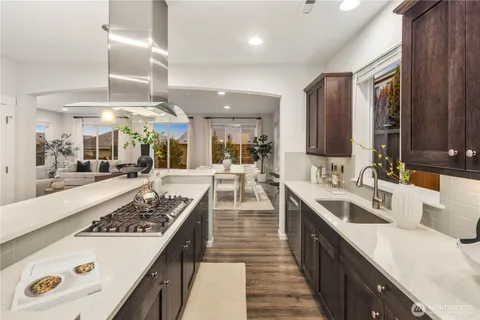 a large kitchen with a large counter top space a sink stainless steel appliances and cabinets