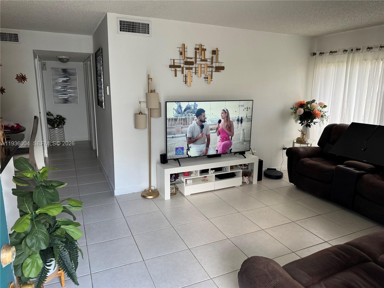 7155 Northwest 179th Street, Unit 112 Hialeah, FL 33015 - Photo 2 of 7 a living room with furniture and a flat screen tv