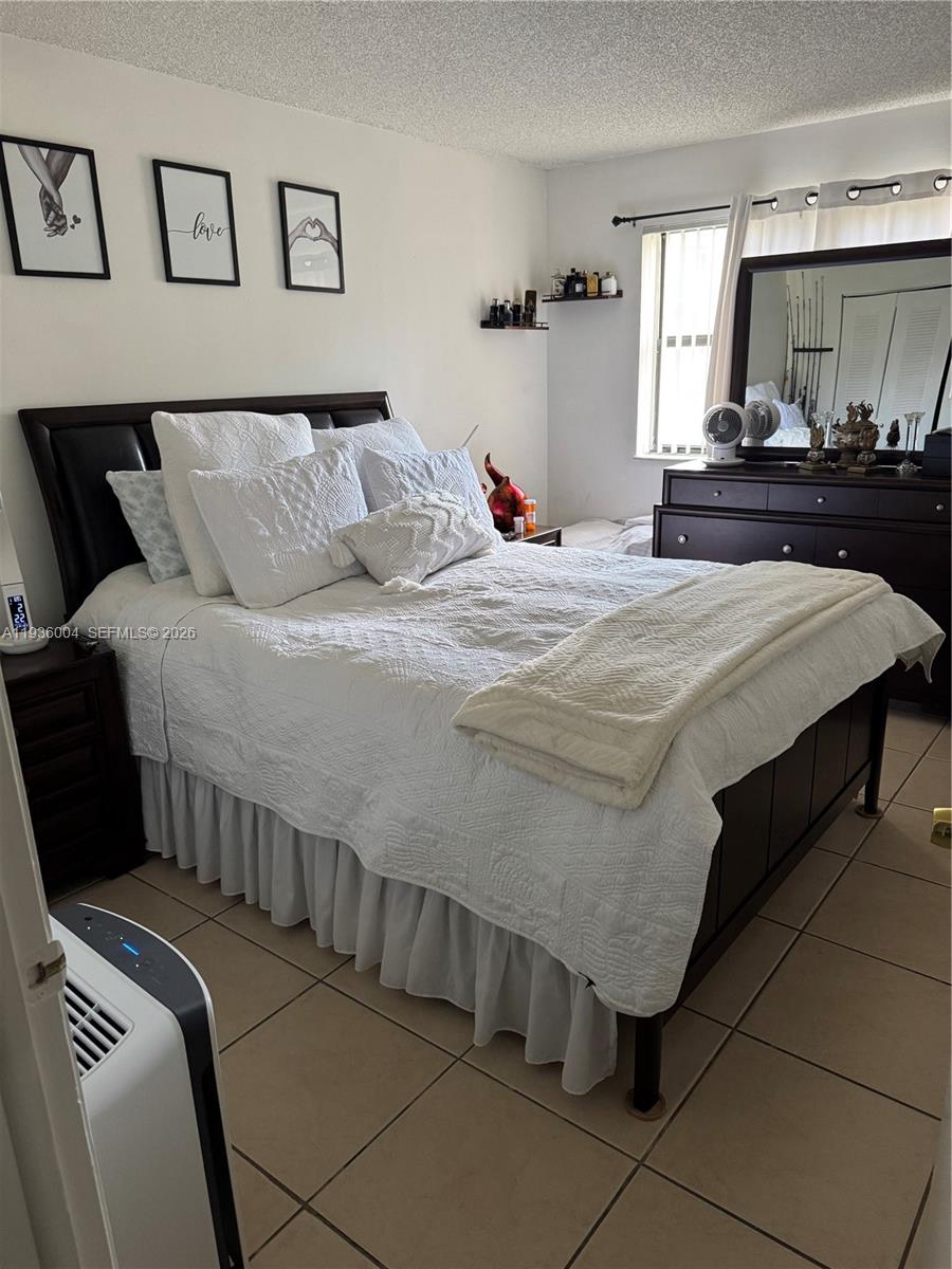 7155 Northwest 179th Street, Unit 112 Hialeah, FL 33015 - Photo 5 of 7 a bed sitting in a bedroom and night stand