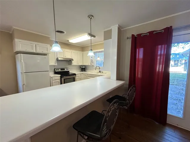 a bedroom with a bed and dresser with wooden floor