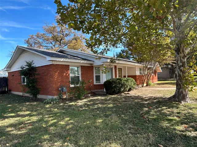a view of a house with a large tree and a yard