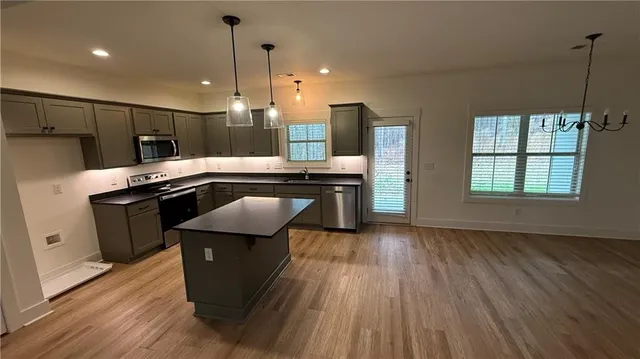 a kitchen with kitchen island wooden floors appliances and cabinets