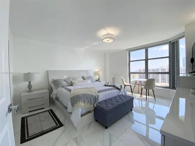 a spacious bedroom with a bed a table and a large window