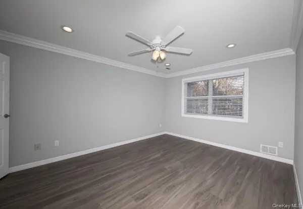 an empty room with wooden floor ceiling fan and windows