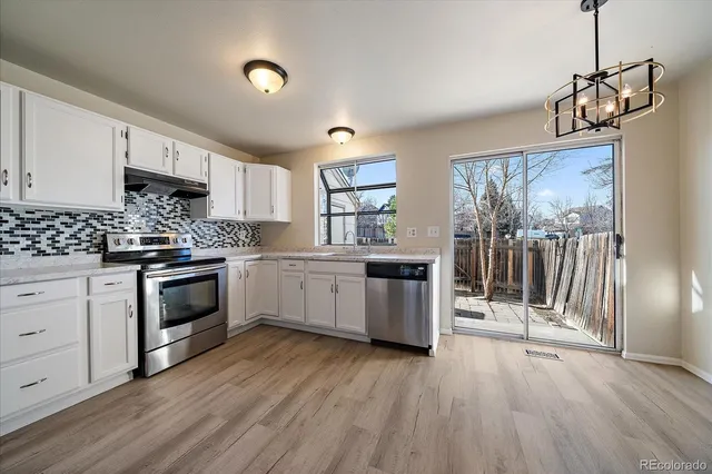 a kitchen with stainless steel appliances granite countertop a stove a sink dishwasher and a refrigerator with wooden floor