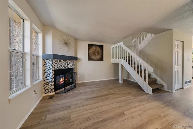 a view of an empty room with wooden floor fireplace and a window