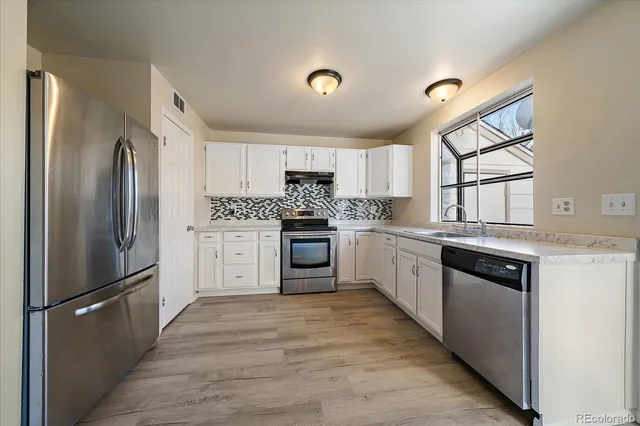 a kitchen with white cabinets and stainless steel appliances