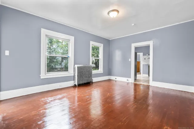 a view of an empty room with window and wooden floor