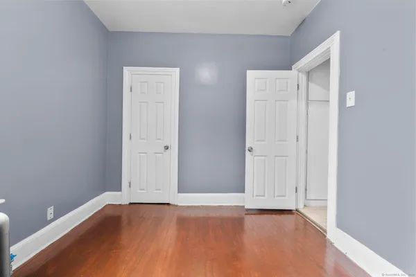 a view of an empty room with wooden floor and closet