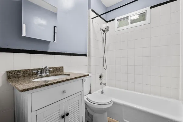 a bathroom with a granite countertop sink a toilet and bathtub
