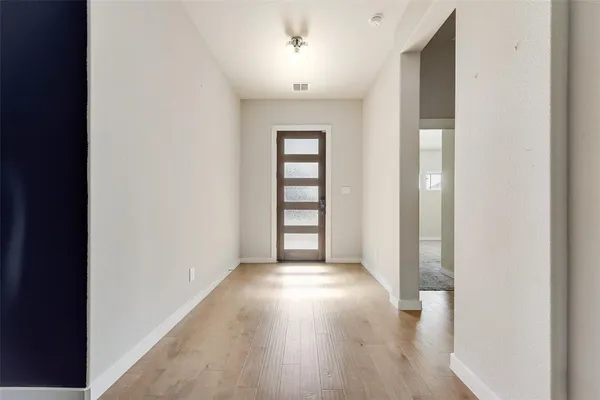 a view of an empty room with a window and wooden floor