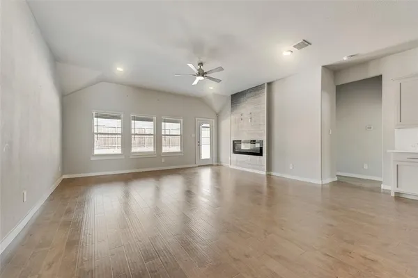 an empty room with wooden floor ceiling fan and windows