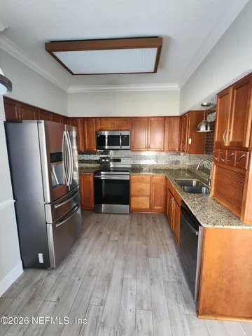 a kitchen with wooden floors and stainless steel appliances