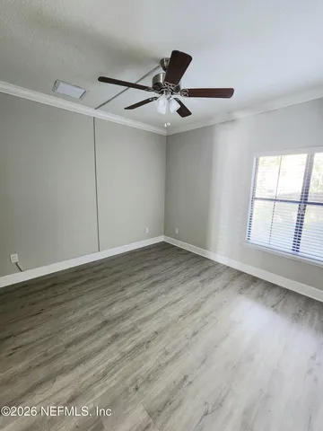 an empty room with wooden floor fan and windows