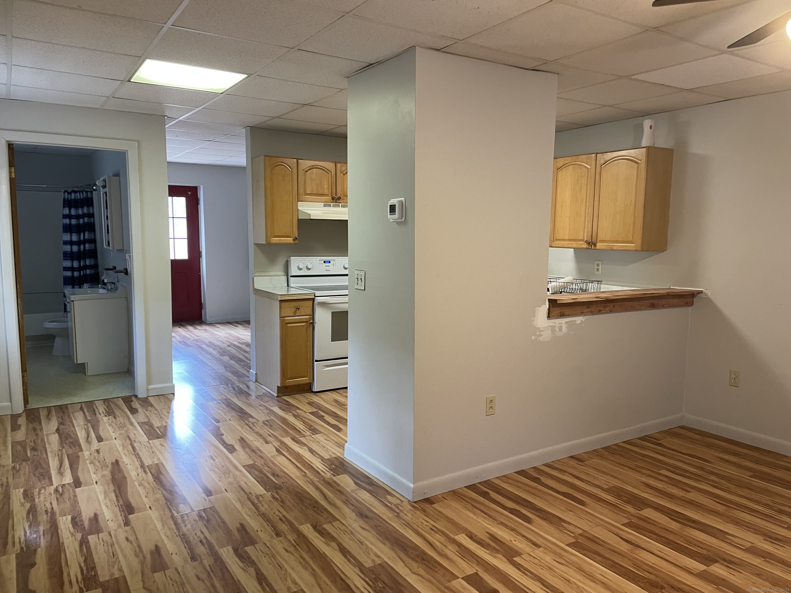an empty room with wooden floor and a kitchen