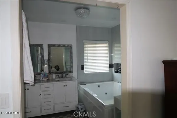 a bathroom with a tub a sink and mirror