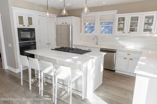 a kitchen with stainless steel appliances kitchen island granite countertop a table chairs and a refrigerator