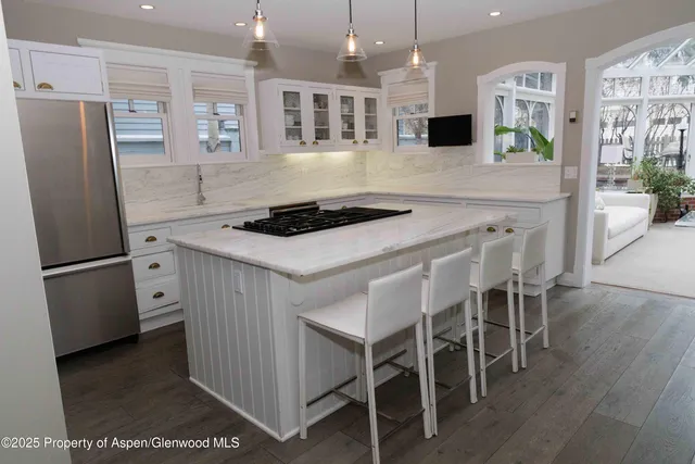 a kitchen with stainless steel appliances a stove a refrigerator a sink a dining table and chairs