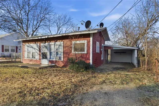 a view of a house with a small yard and large tree