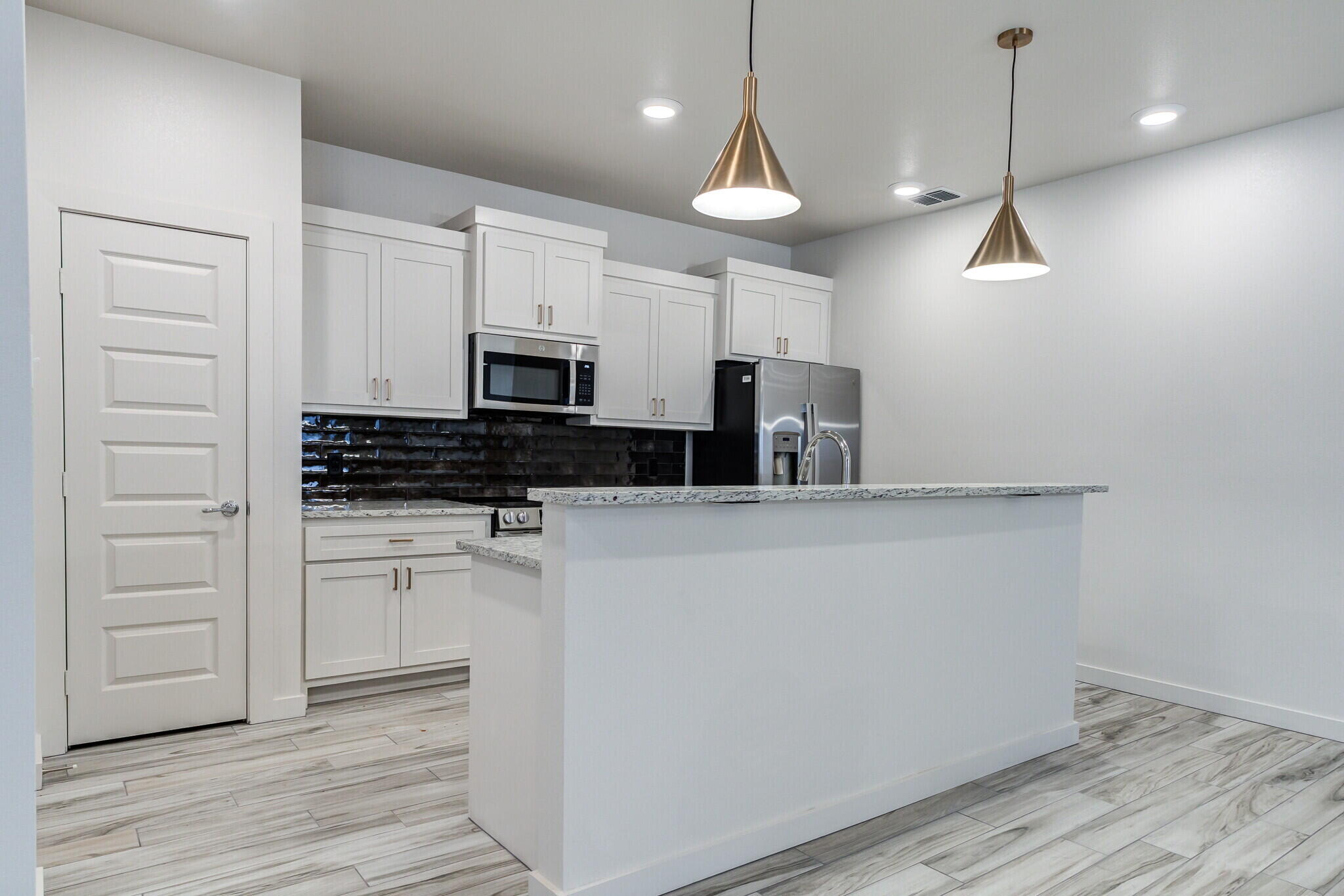 7048 41st Street Lubbock, TX 79407 - Photo 11 of 34 a kitchen with a refrigerator a stove and white cabinets with wooden floor