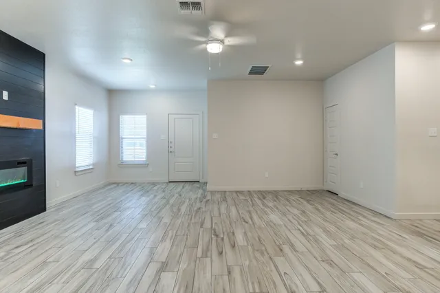 an empty room with wooden floor fireplace and windows